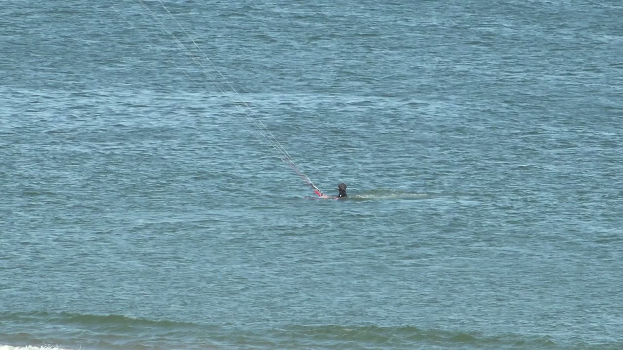 Small kite surfer with board on rippled ocean