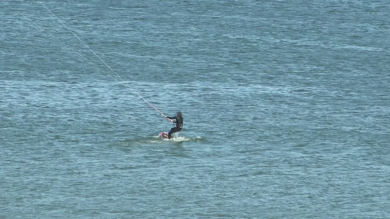 Kite surfer lifting slightly above the water on a board.