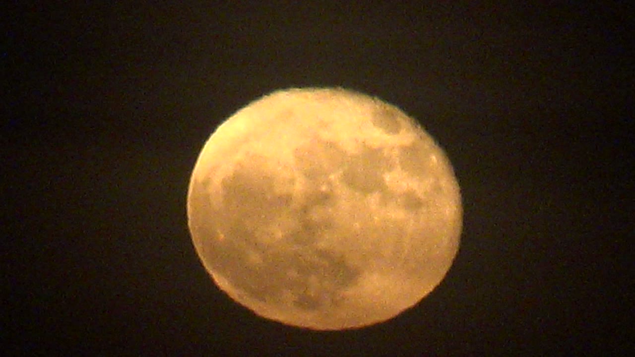 Warm yellow-orange full moon over La Bocana, Baja California Sur, centered against a dark sky with crater texture visible and no visible people.