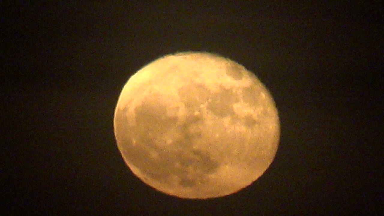 Full moon glowing orange in a black sky.