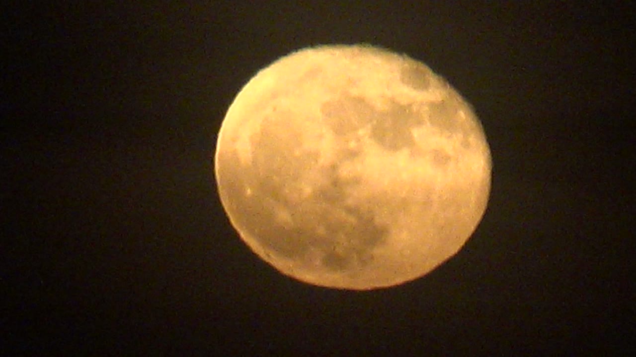 Full moon with soft cloud haze across the surface.
