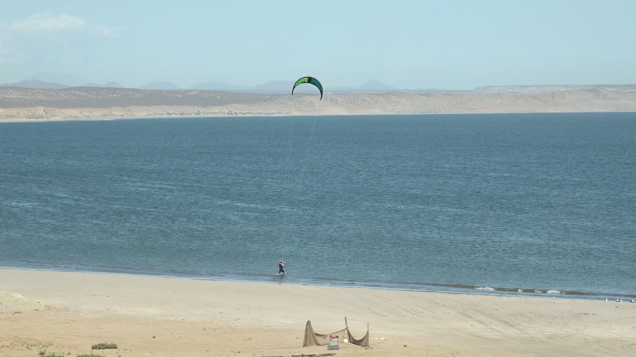 Distant kitesurfer near the shoreline with kite centered above the water.