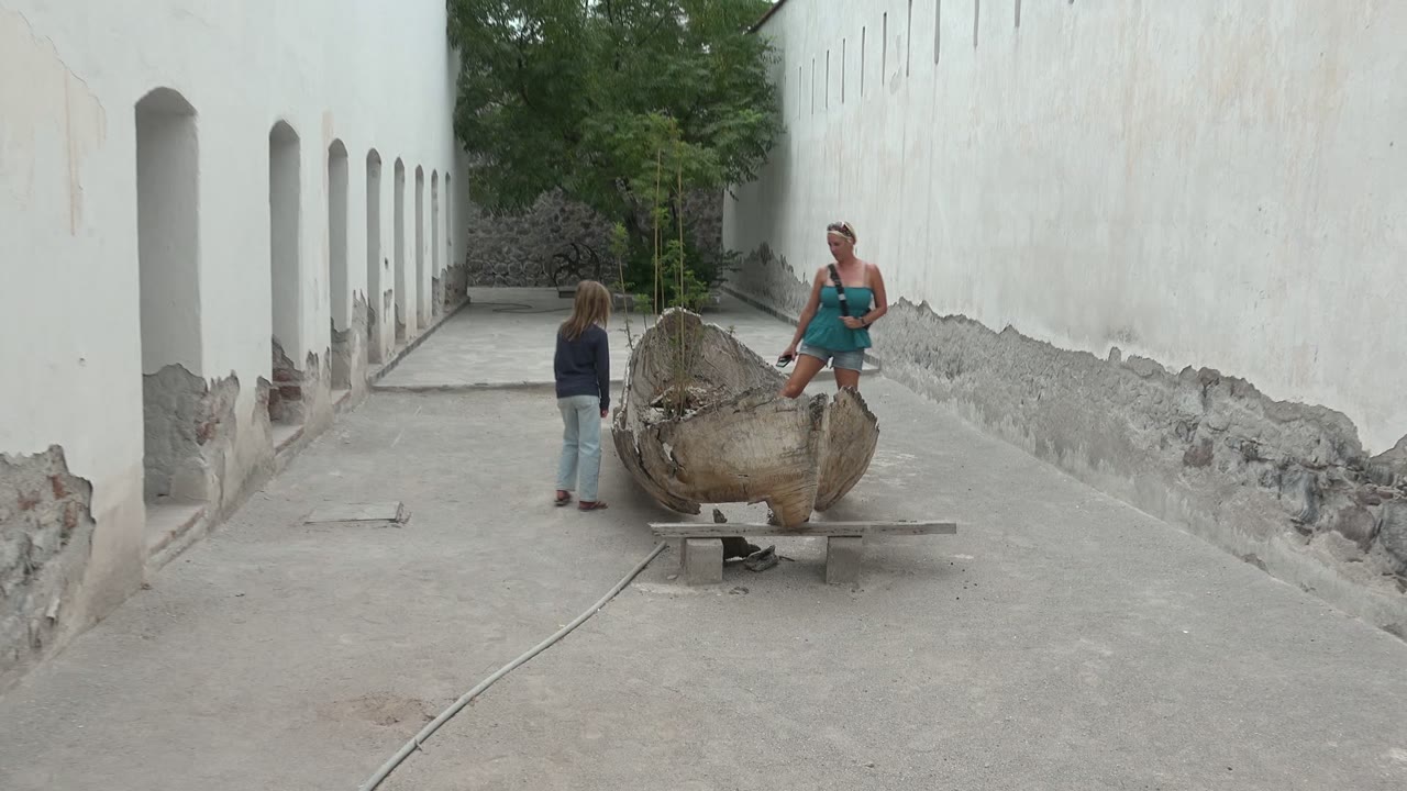 In Mulege, Mexico, the adult stands next to the shell sculpture as the child faces her across the concrete courtyard.