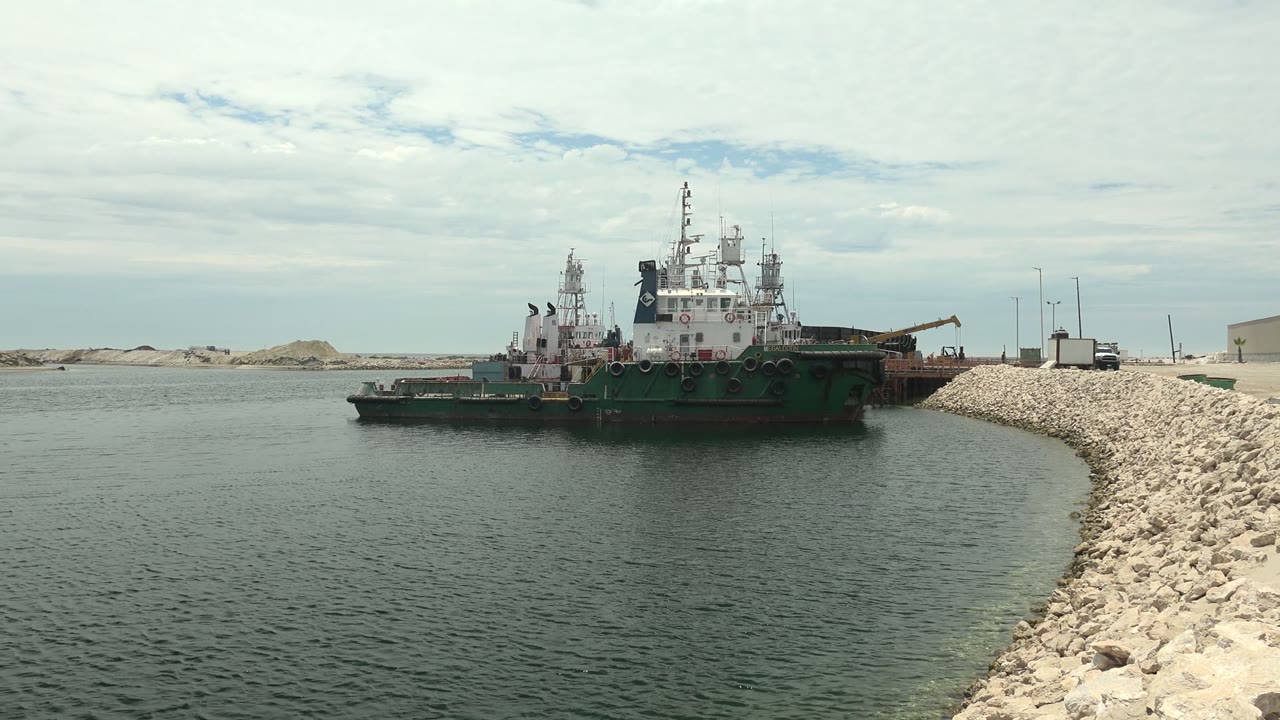 Large vessel near breakwater under cloudy sky