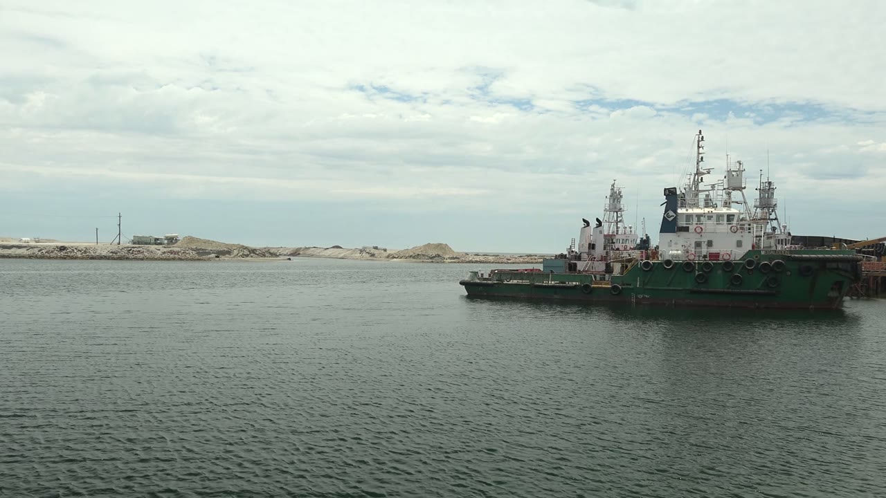 Tugboat drifting left across rippled harbor water.