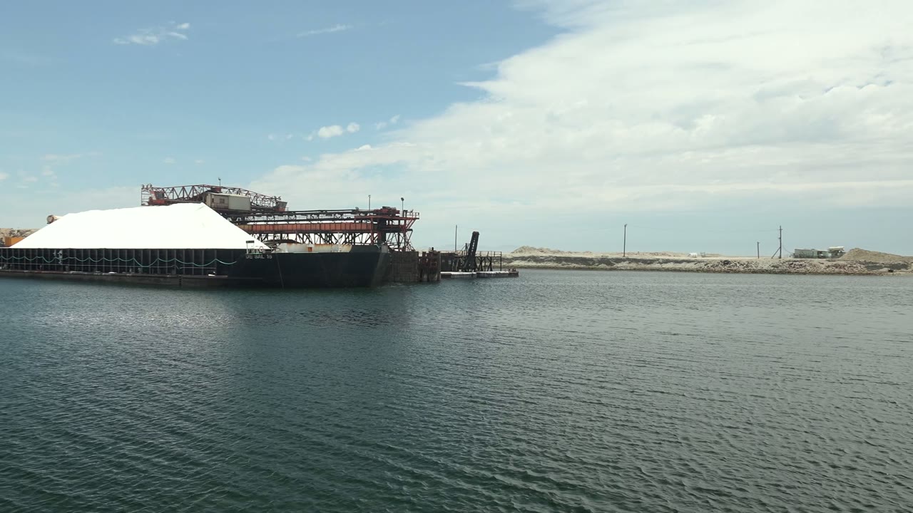 White-covered barge with red crane structure over calm water