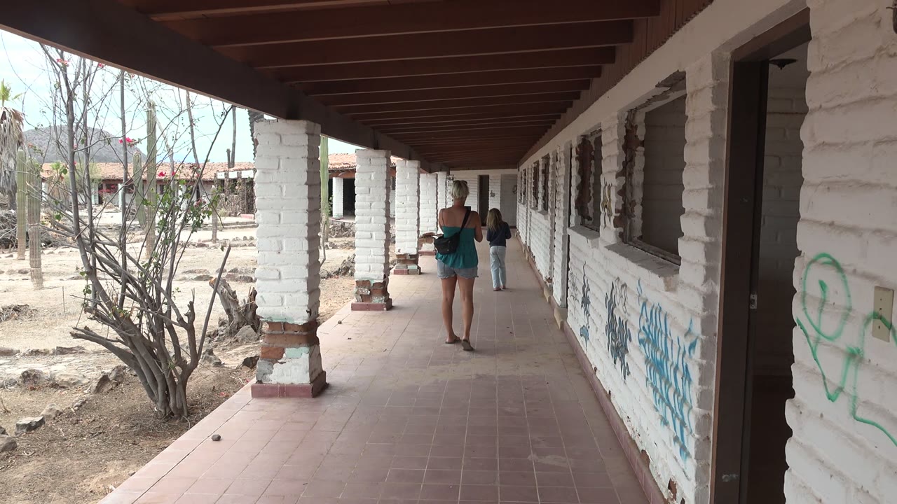 Walkers farther down a shaded tiled corridor beside graffiti walls.
