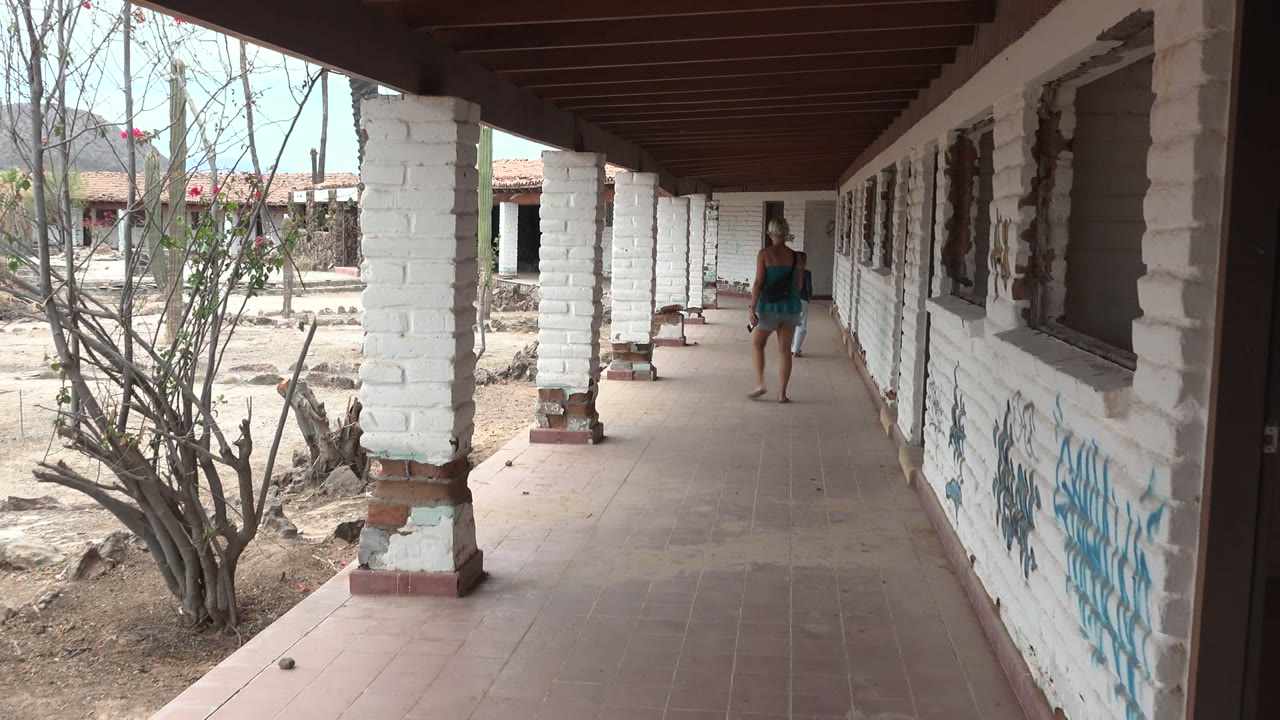 Walker farther down a tiled corridor with graffiti on the wall.