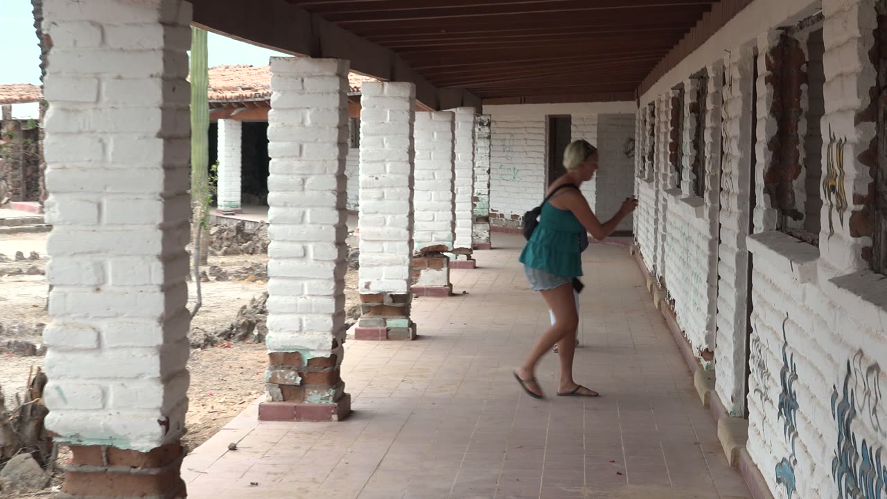 Woman stands near the corridor wall after the child has moved out of frame.