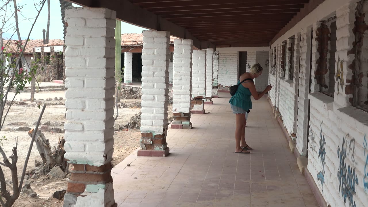 Woman examines the wall beside a white brick column and courtyard.