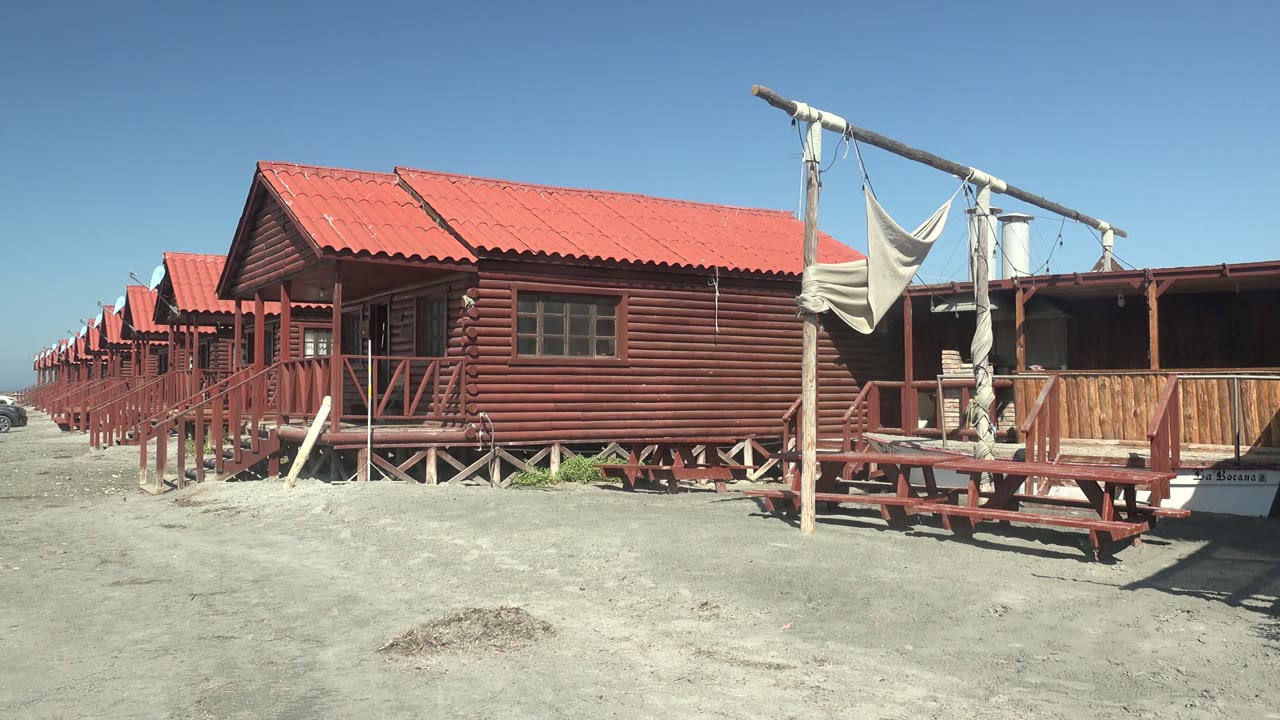 Red-roofed wooden cabins with porch structures and sandy foreground.