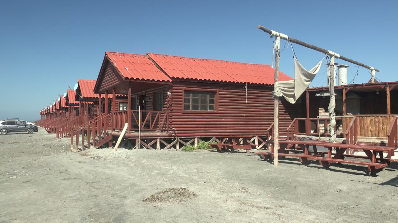 Cabin row with a car entering the left background.