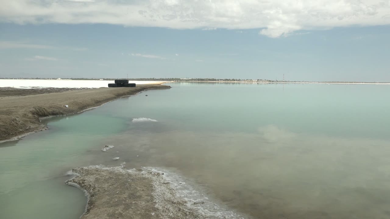 Calm turquoise water with shore crust and platform near the horizon.
