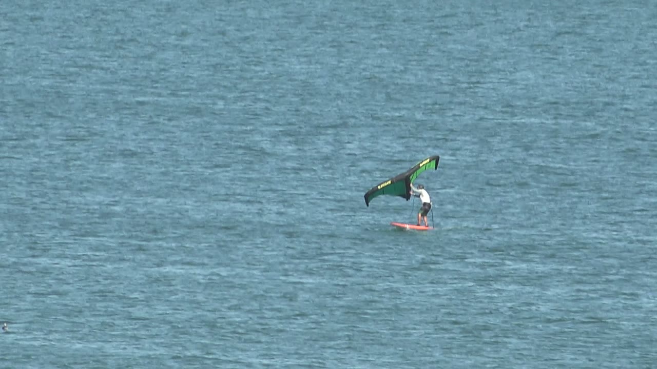 Kite surfer riding alone across a wide ocean frame.