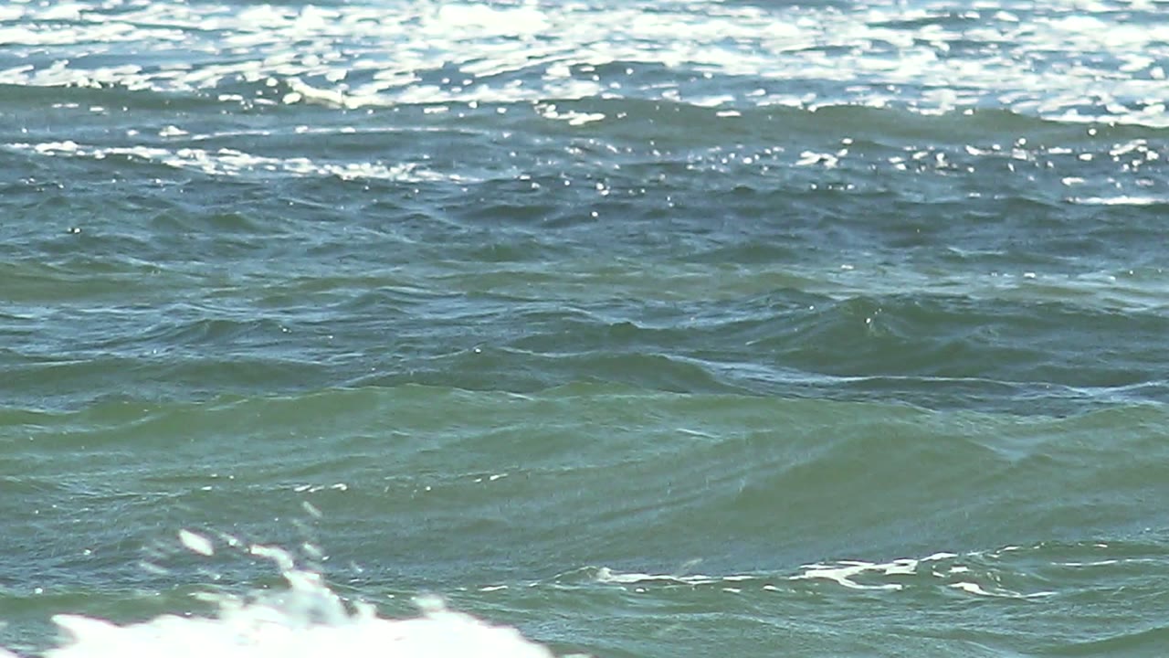 Blue-green ocean water at La Bocana, Baja California Sur, with a broad white foam line across the middle of the frame and no visible people.