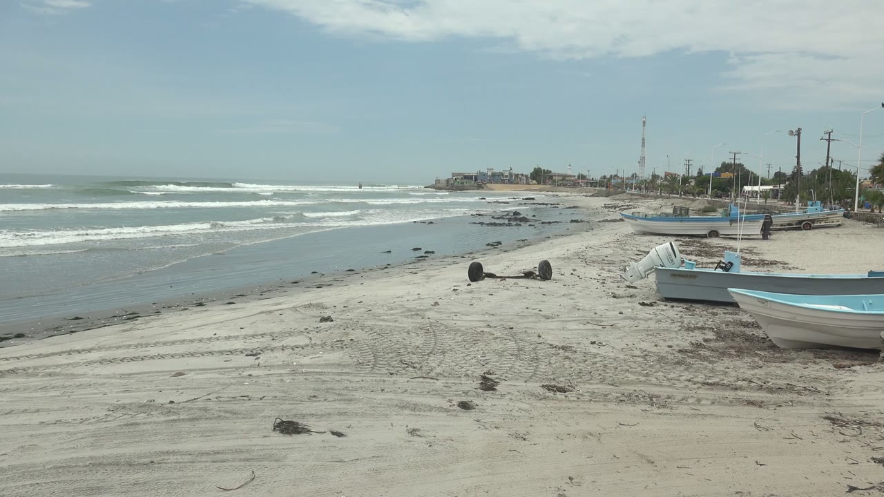 Parked boats on sandy shore beside breaking waves
