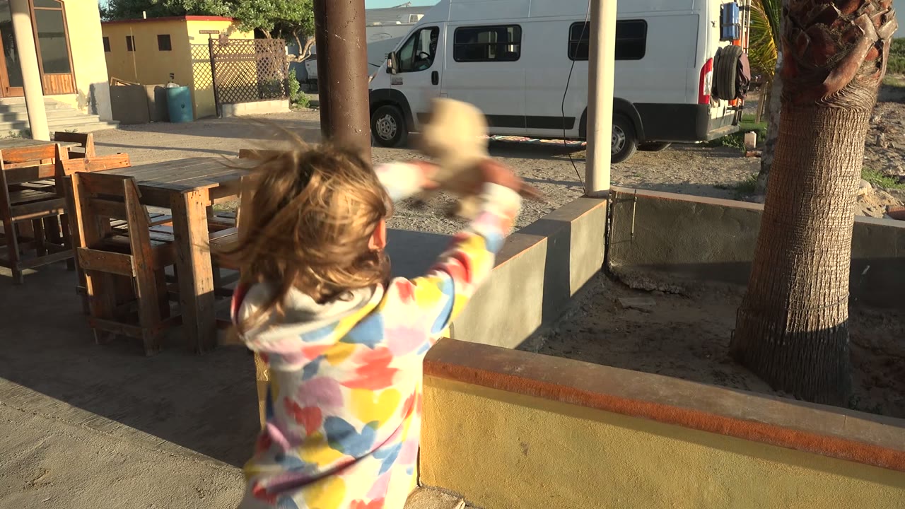 Child turned away while holding a rabbit near a patio wall.