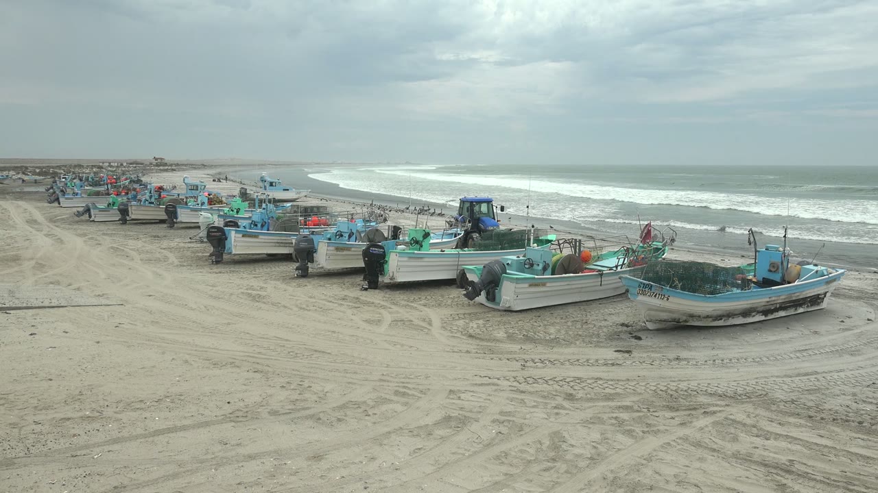 Small fishing boats on sand with gray surf behind