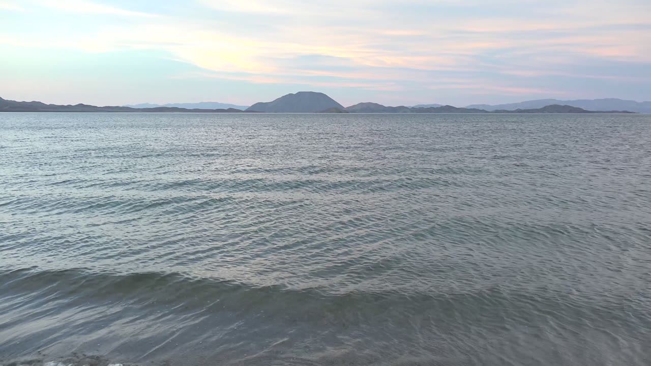 Low ocean swell beneath a soft sky and distant island horizon.