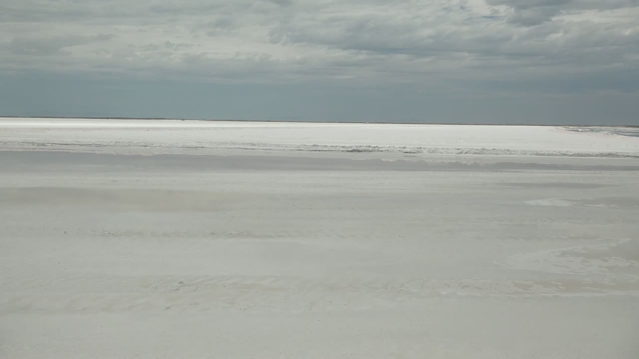 Wide view of a pale frozen river surface in Guerrero Negro, Baja California Sur, with a flat horizon, heavy gray clouds, and no visible people.