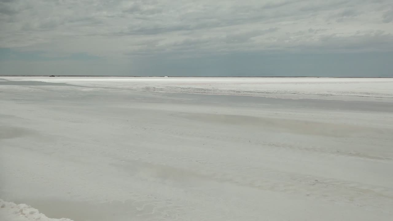 White textured expanse with a thin horizon and muted sky.