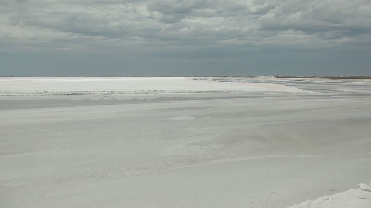 Wide view of frozen water and snow near Guerrero Negro, Baja California Sur, with a low landmass on the horizon and no visible people.