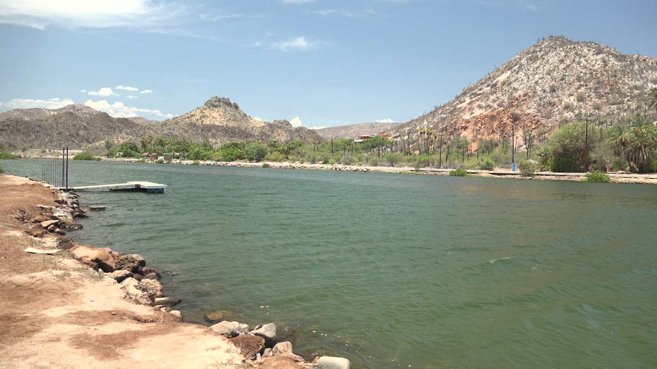 Small dock on green water with mountains across the shore
