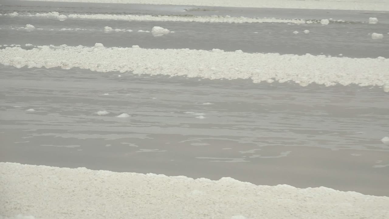 Salt crust and shallow water with a distant flat horizon.