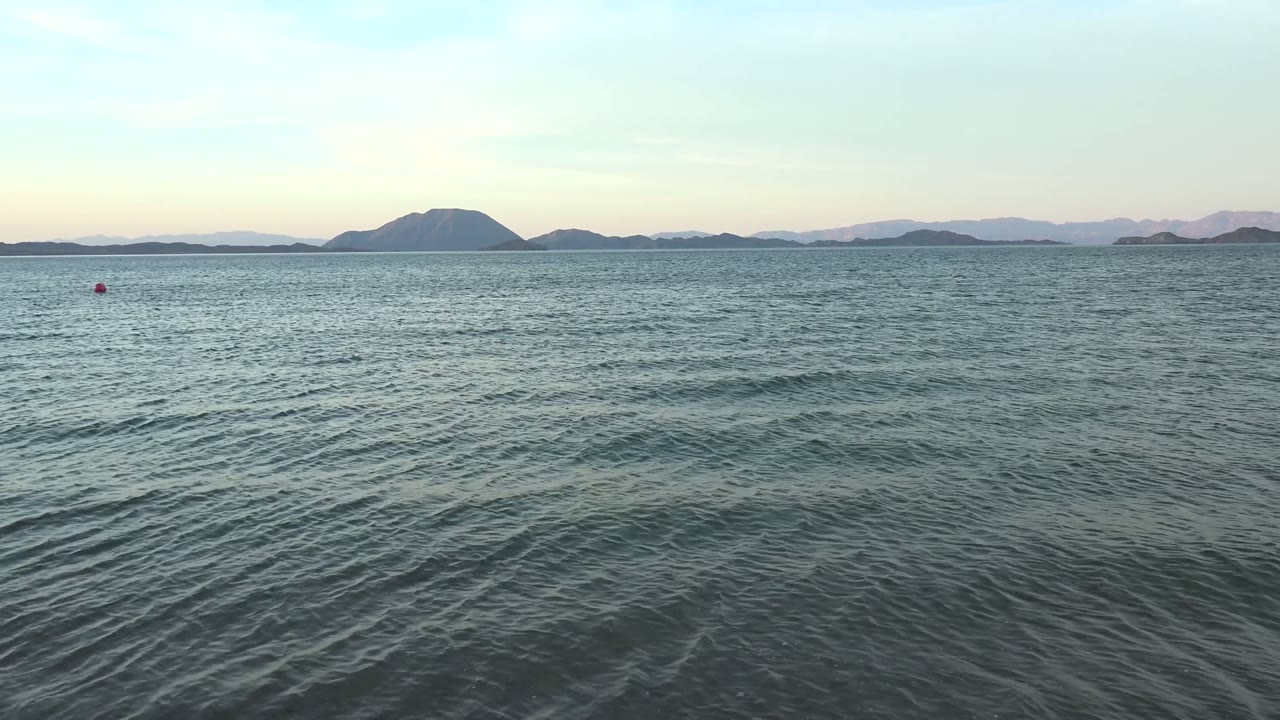 Blue-green ocean surface with a low island chain on the horizon.