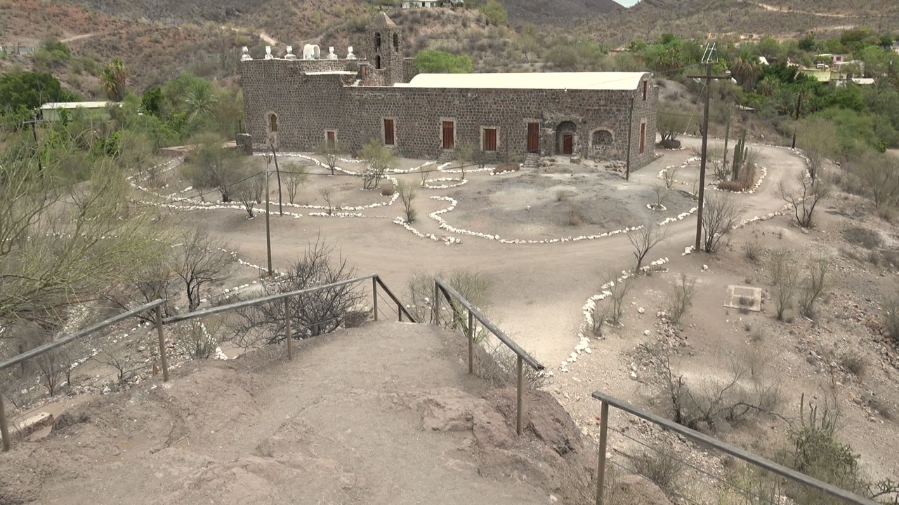 Desert courtyard path leading toward a stone mission building