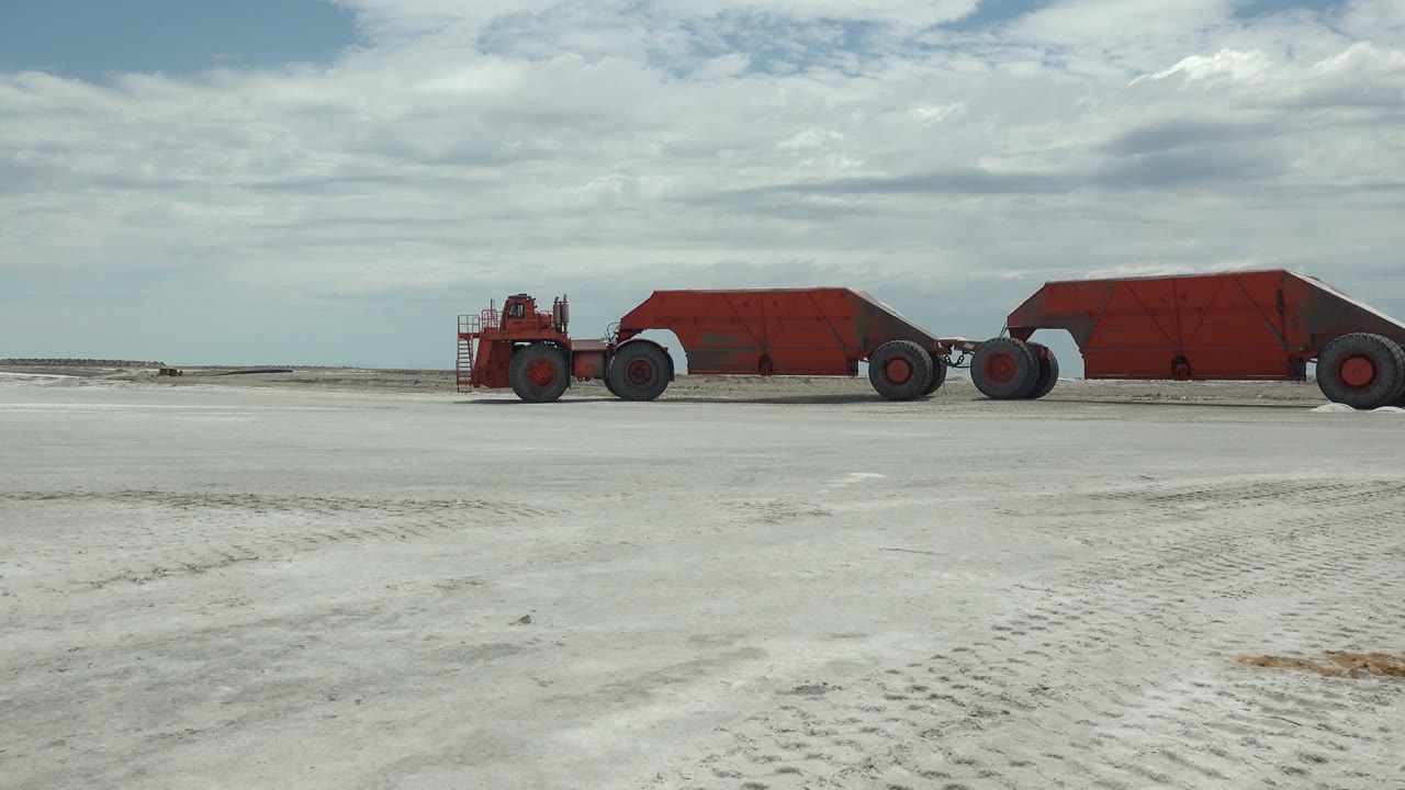 Red hauler and trailers continue across the open white surface.
