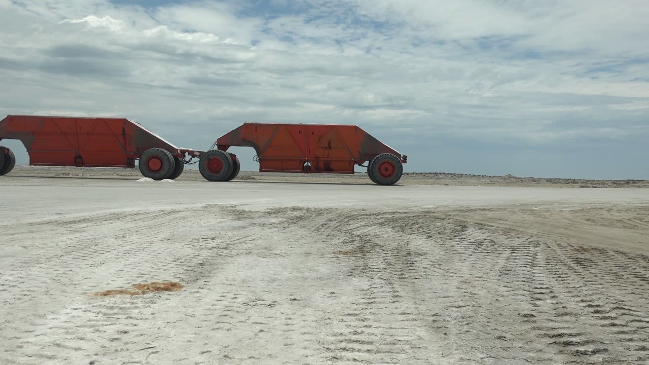 At the start of the Guerrero Negro clip, a rusted red vehicle spans the left and center of the frame on pale sandy terrain with tire tracks and no visible people.