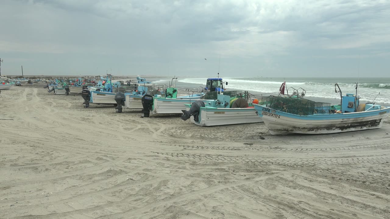 Beached fishing boats fill the midground at Punta Abreojos while tracked sand leads toward the shoreline and bright surf runs across the right background.