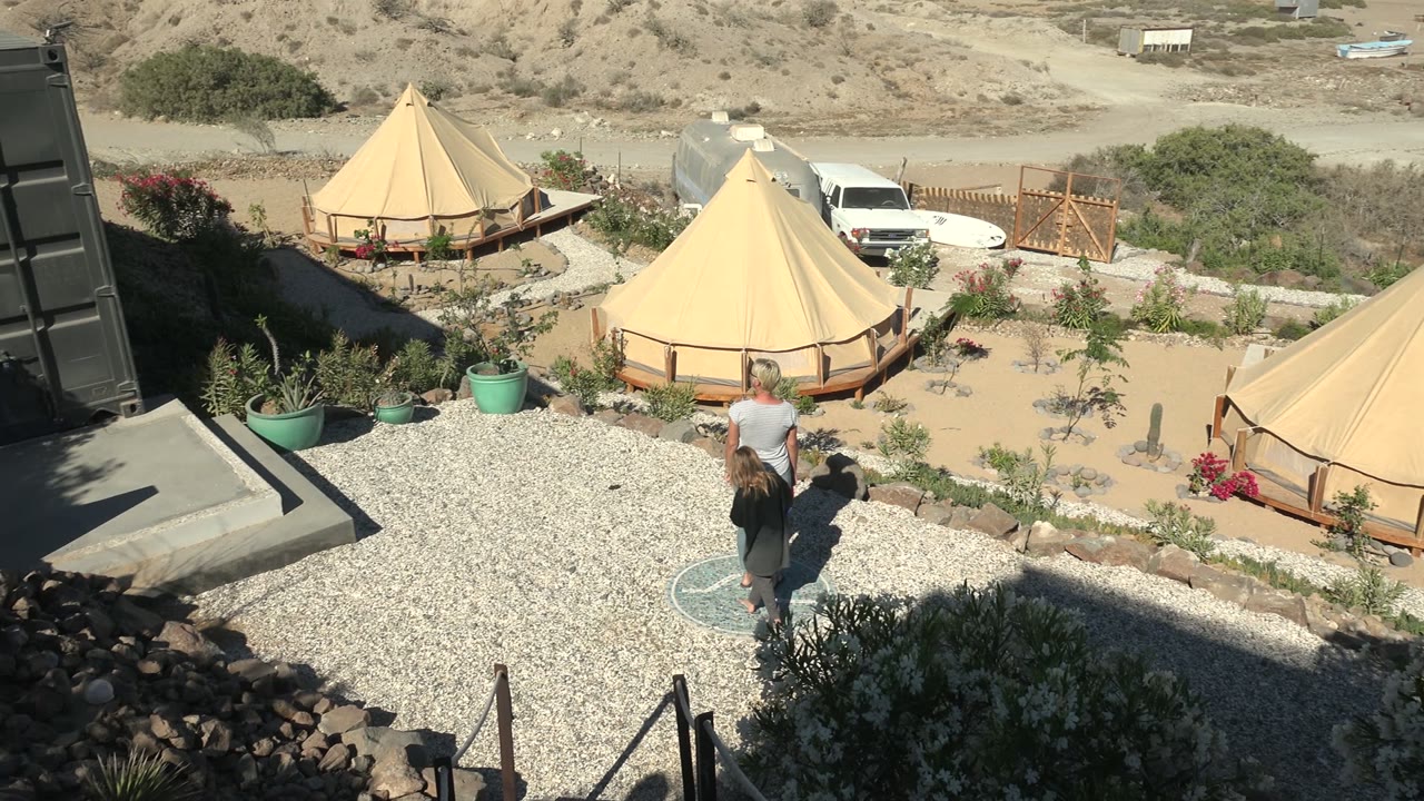 Adult and child continue along a gravel path near desert yurts.