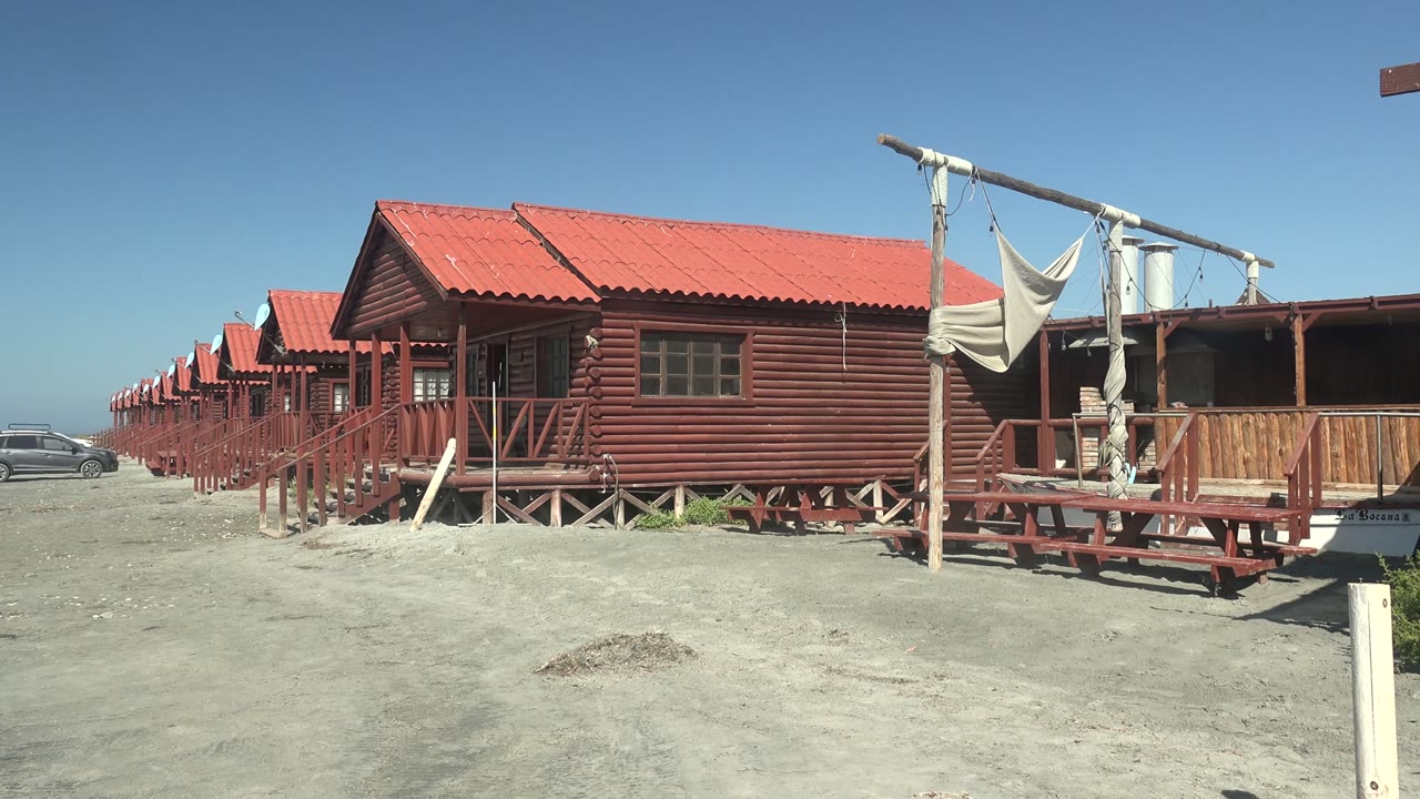 Row of red cabins with car moving farther left