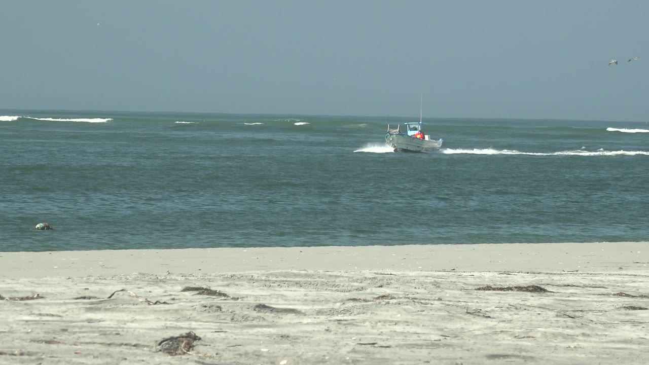 Boat crossing nearshore water with surf lines behind it
