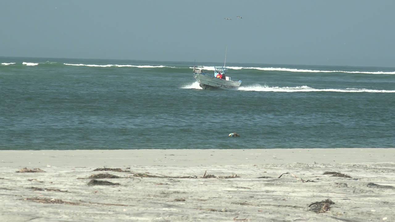 Boat farther right on the ocean with wake trailing behind.