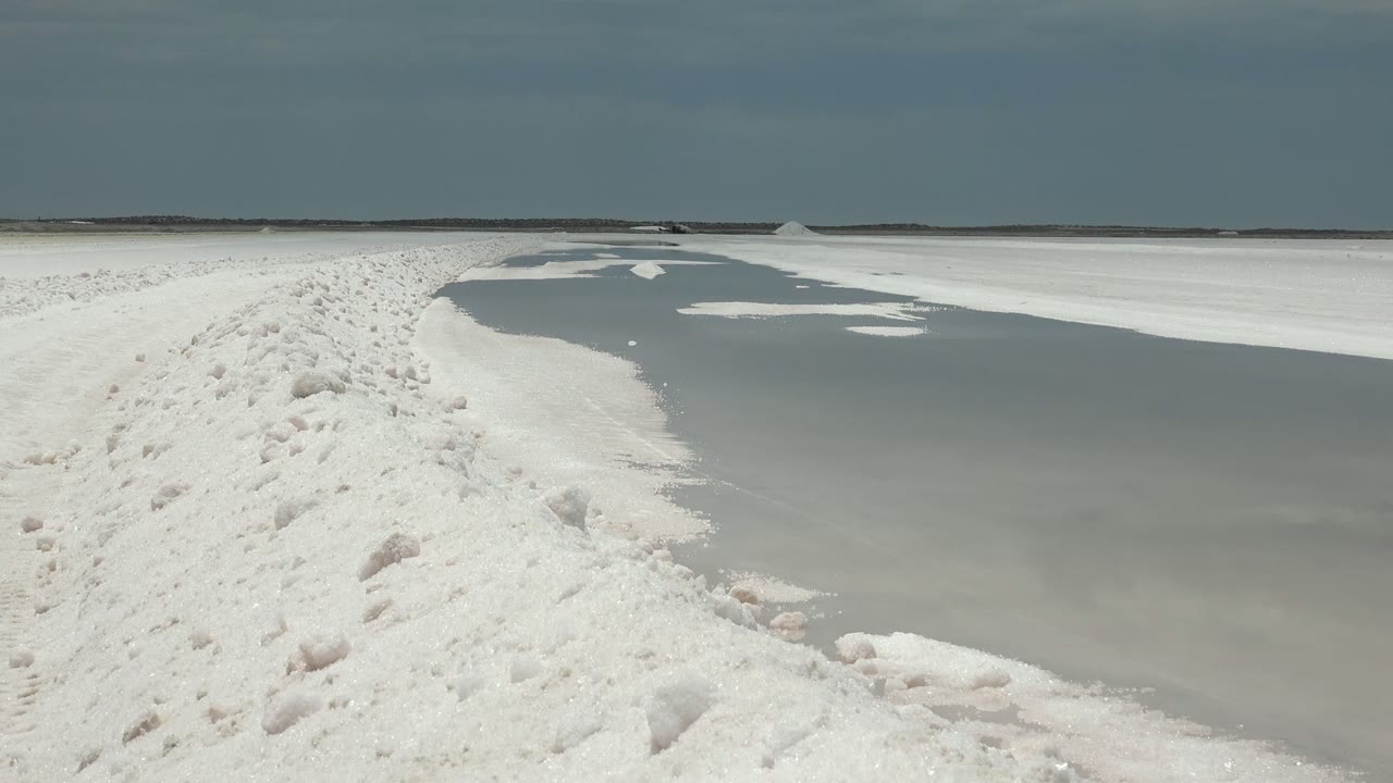 Frozen channel curving beside a white footprint path.