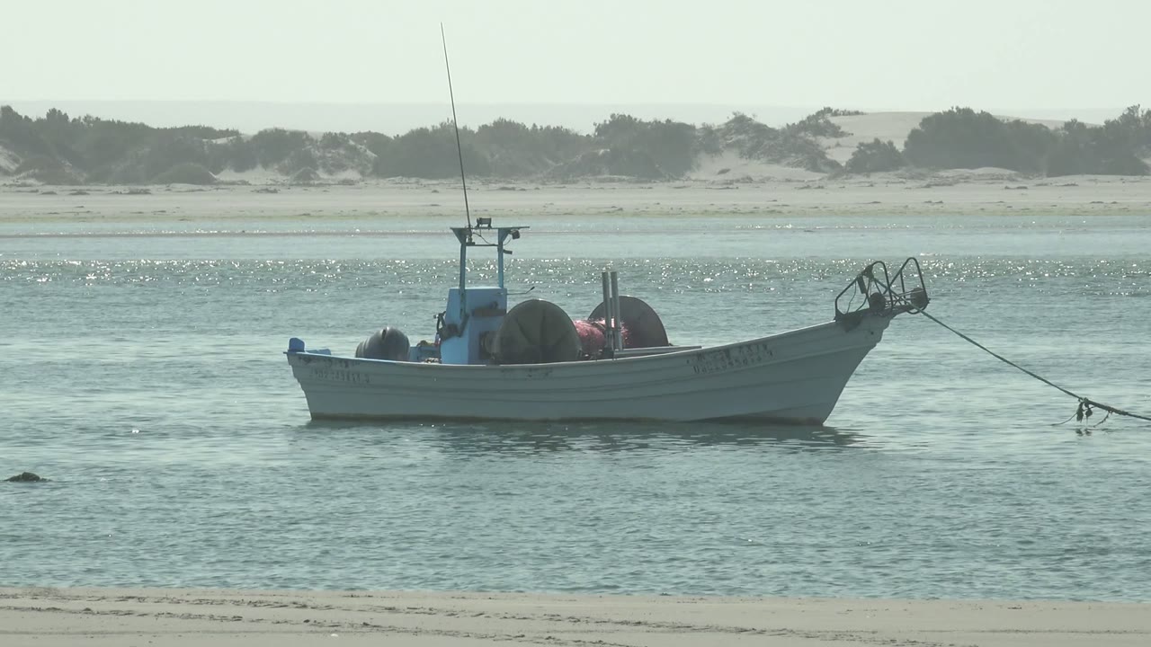 At 0:02, the boat sits slightly right of center in La Bocana's shallow coastal water, with its bow line visible and no people in frame.