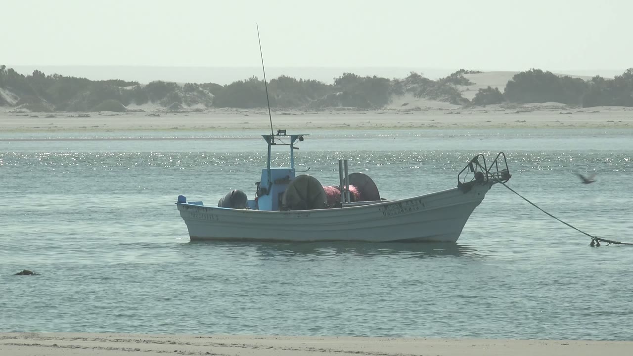 Anchored boat with rope extending across calm shallow water