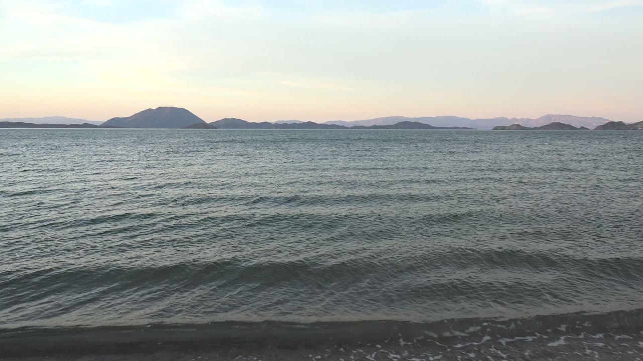 Rippling Bahia De Los Angeles water fills most of the frame, with a small wave crest near shore, muted island silhouettes in the distance, and no visible people.