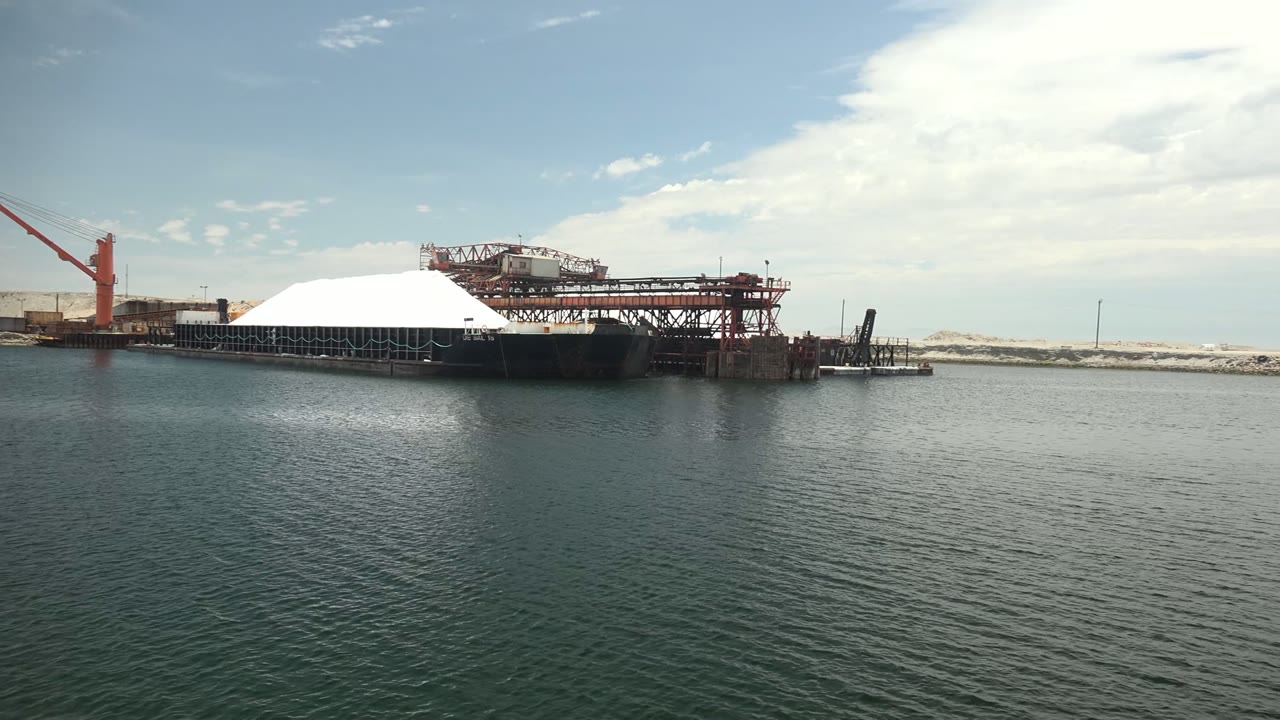 Red crane and metal dock framework across still harbor water.