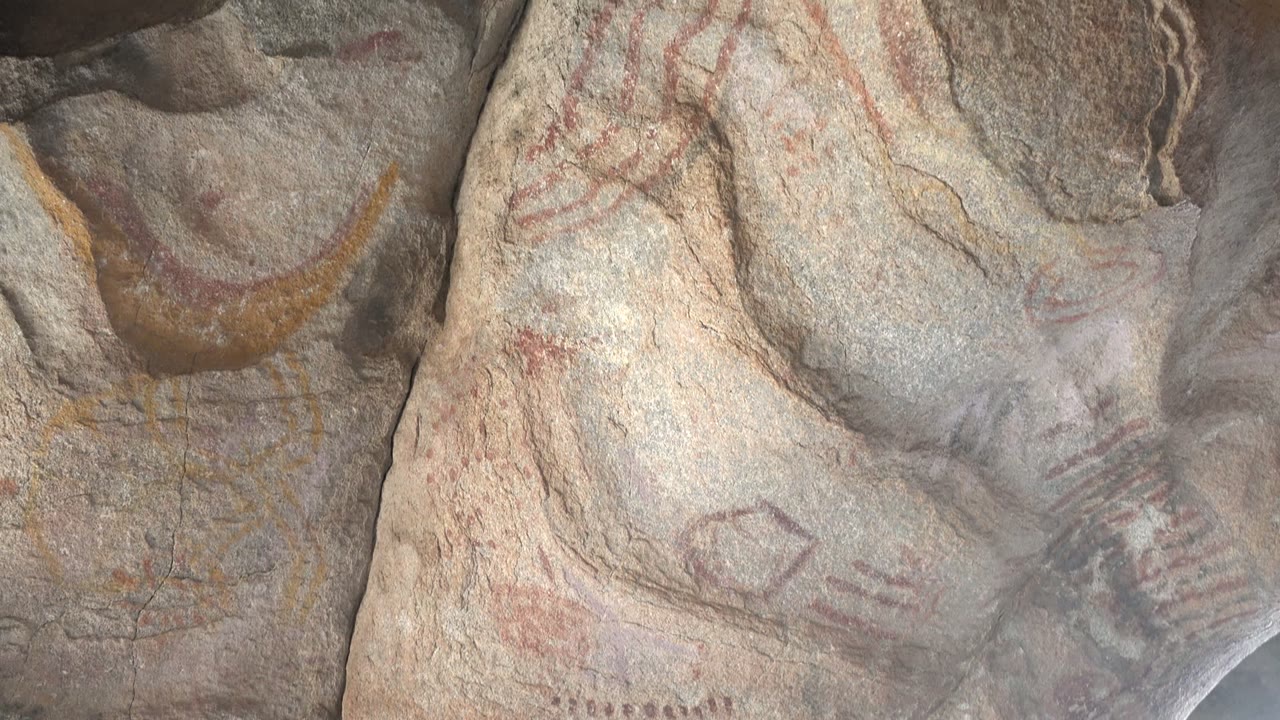 Faded red lines and yellow pigment on rough stone