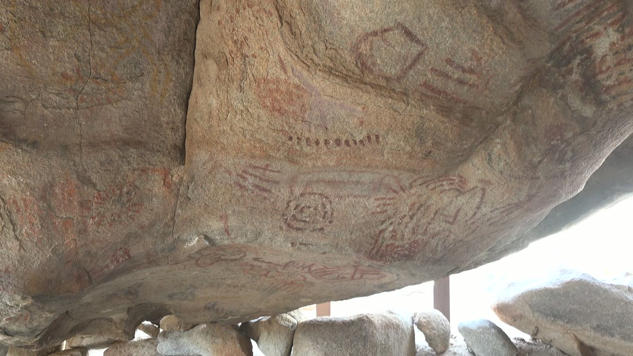 Faded rock art symbols on rough stone overhang