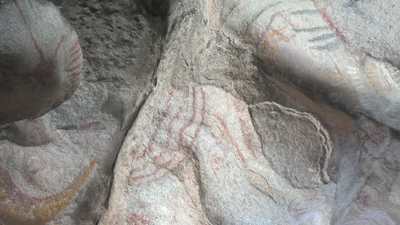 Close stone surface with red handprints and blue-gray pigment traces