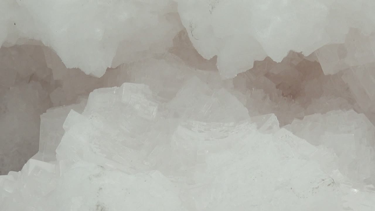 Opening frame of white and translucent ice crystals in Guerrero Negro, Baja California Sur, Mexico, with jagged edges and pale gray pockets, no visible people.