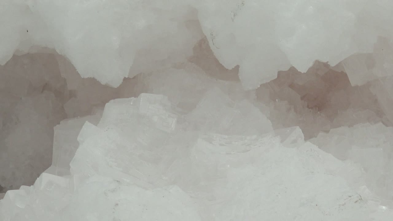 Close-up ice texture from Guerrero Negro with broad white crystal masses, faint gray shadows between forms, and no visible people.
