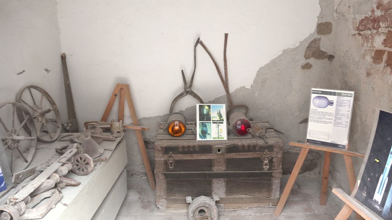 Old tools and display easels arranged against a worn plaster wall.