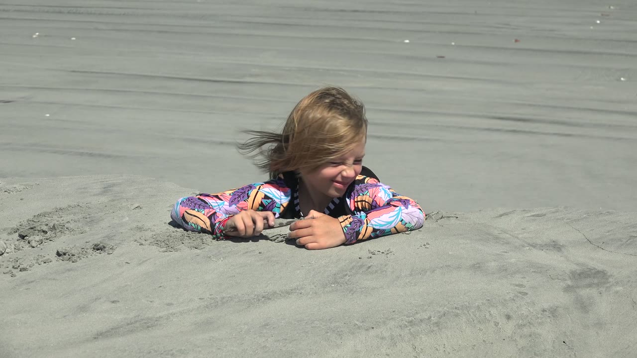 Child smiling while playing with sand on the beach