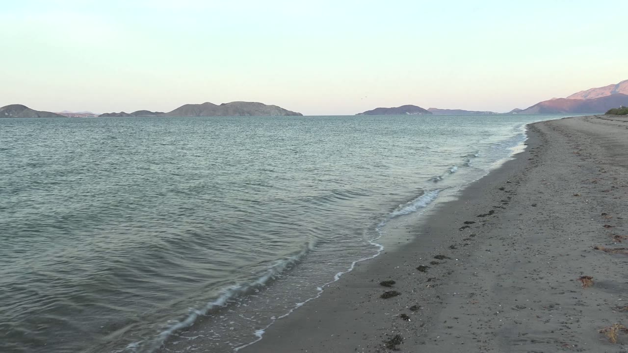 At two seconds, a wider curve of foam follows the Bahia De Los Angeles beach edge, with green-blue water beside the sand, distant mountains, and no visible people.